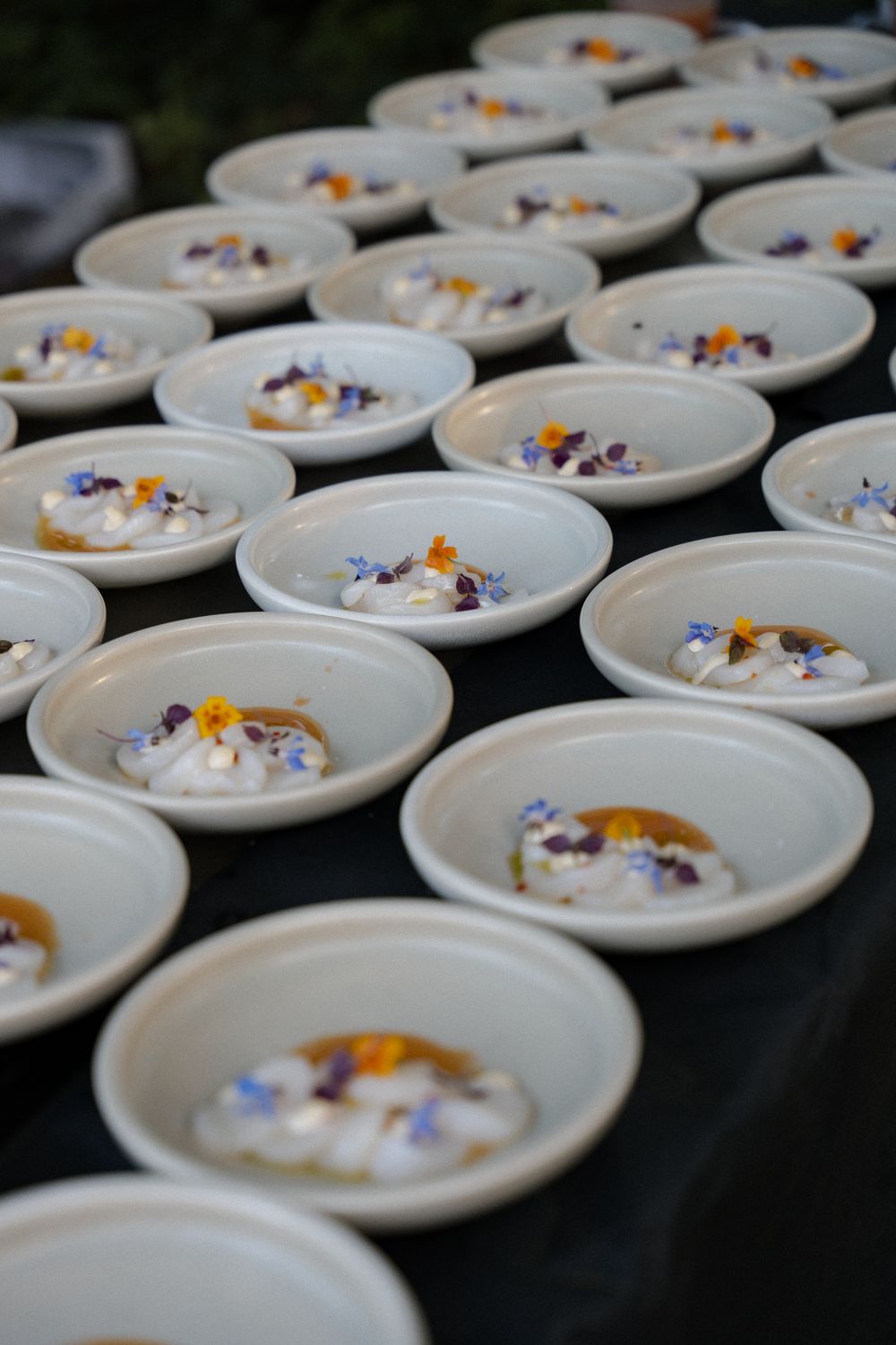 Rijen schaaltjes visceviche met eetbare bloemen, klaar voor service