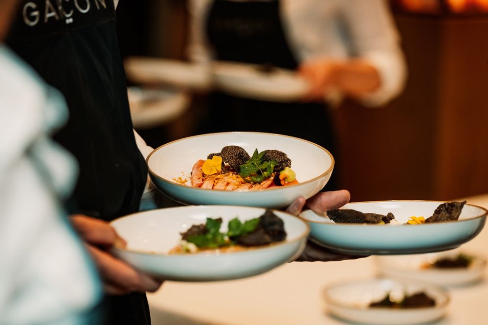 Borden met gemarineerde vis en geschaafde zwarte truffel, gedragen door een kelner