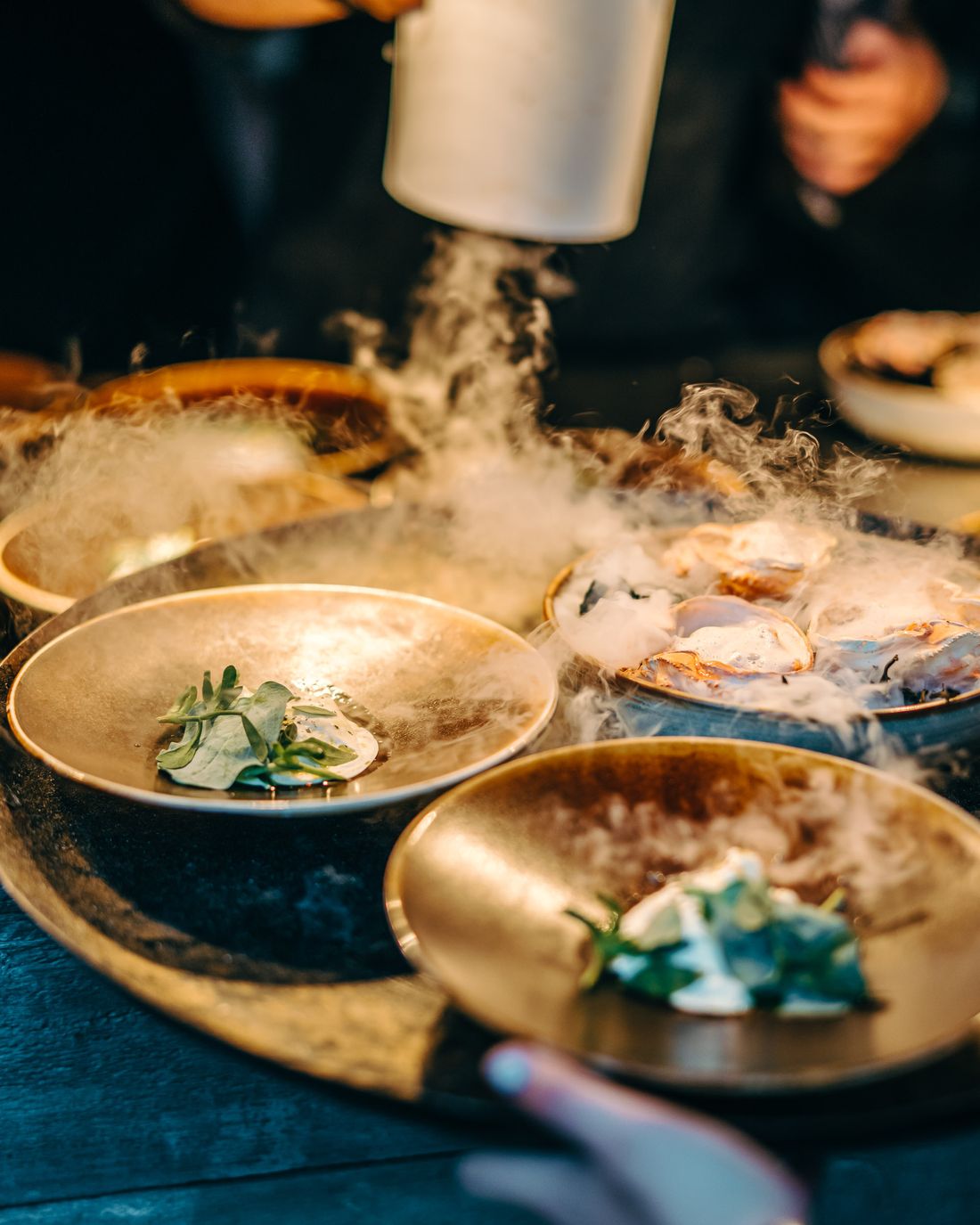 Rokende gerechten in gouden schalen op een donkere feesttafel