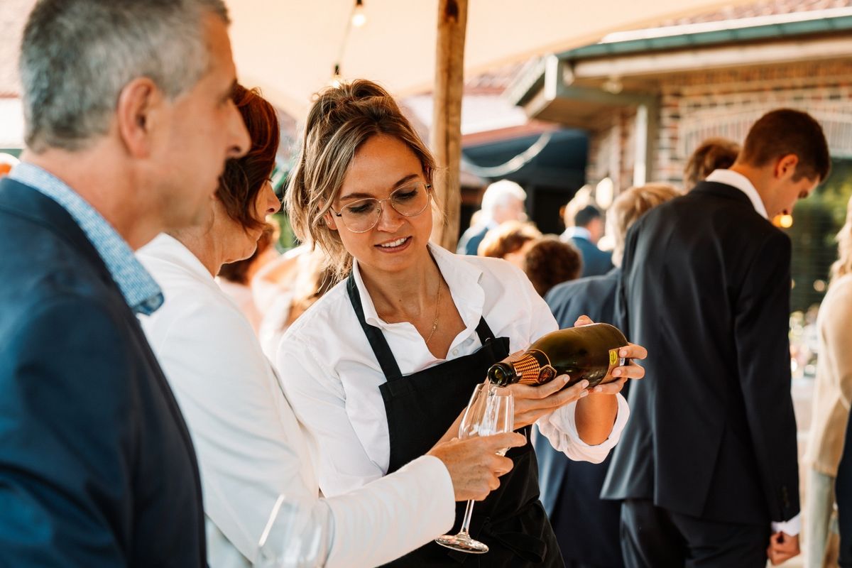 Kelner schenkt schuimwijn voor gasten tijdens een receptie